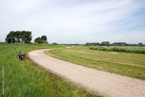 Fototapeta Naklejka Na Ścianę i Meble -  Dutch dirt road through the meadows along the Ringvaart of the Bergermeer near the village of Bergen in summer. July, Netherlands.