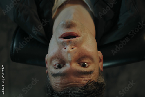 A man snorts cocaine while sitting at his desk in his office and tilts his head back as he gets high. Closeup portrait of a man high on drugs  photo