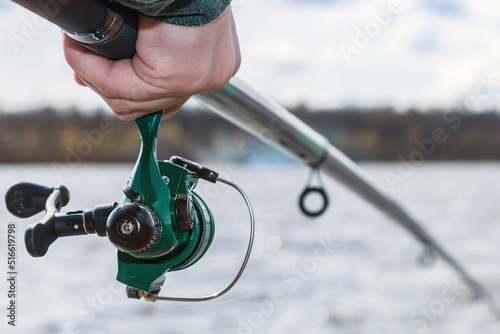 Fototapeta hand holding a fishing rod with reel