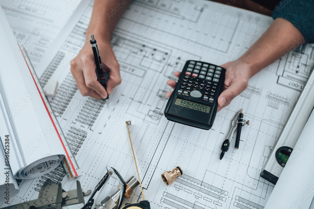 Engineering working with drawings inspection and press calculator on the office desk and triangle ruler, safety glasses, compass, vernier caliper on Blueprint. Engineering working with drawings inspection and press calculator on the office desk and triangle ruler, safety glasses, compass, vernier caliper on Blueprint.