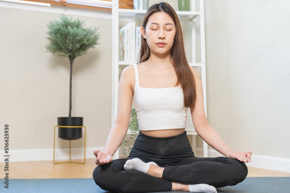 Workout, calm asian young woman, girl hand in calm pose sitting practice meditating in lotus position on mat at home, meditation, exercise for wellbeing, healthy care. Relaxation, happy leisure. Workout, calm asian young woman, girl hand in calm pose sitting practice meditating in lotus position on mat at home, meditation, exercise for wellbeing, healthy care. Relaxation, happy leisure.