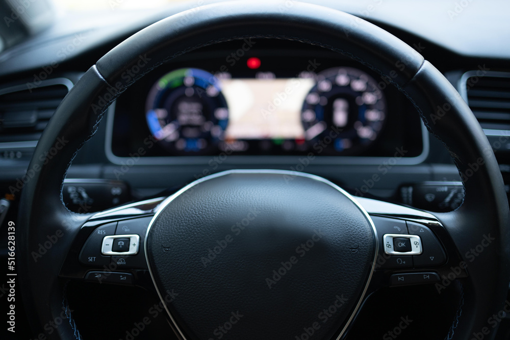Close up of steering wheel of a new electric vehicle, interior cockpit, electric buttons, digital speedometer. Electric car control devices. Cruise control buttons, speed limitation, car's signal