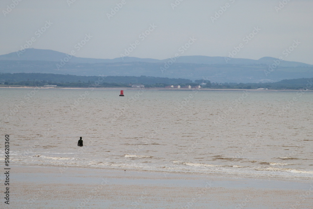 A beautiful landscape shot of Crosby Beach during an overcast summer day. The famous Iron Men can be seen in this image.
