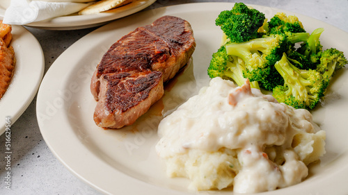Country grill steak served with mashed potatoes and gravy, and broccoli close up