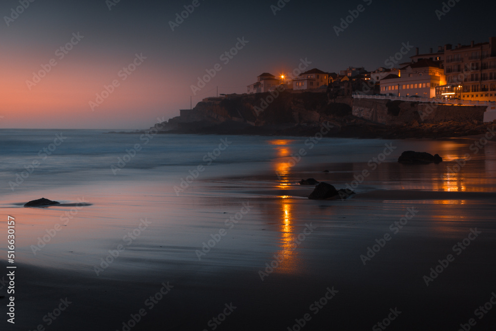 Amazing landscape of the Atlantic ocean coast at sunset.  View of colorful dramatic sky and buildings near a sandy beach. Long exposure image. Beach of Praia das Macas. Portugal.