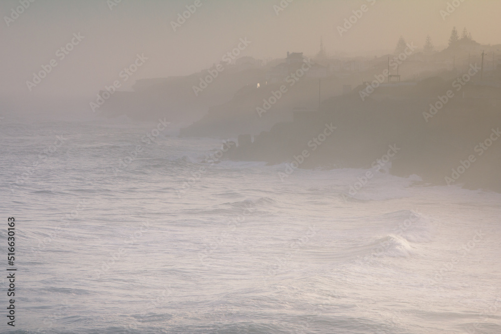 Amazing landscape of Atlantic ocean at sunrise. View on morning fog, big waves and stony coast. Beach of Praia das Macas. Colares. Portugal. Concept travel of Europe. 