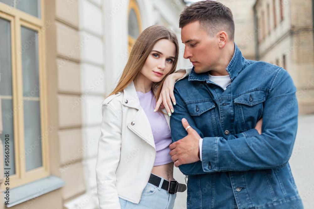 Beautiful trendy young stylish models couple woman and man in fashionable street denim clothes are walking near a vintage building in the city Beautiful trendy young stylish models couple woman and man in fashionable street denim clothes are walking near a vintage building in the city