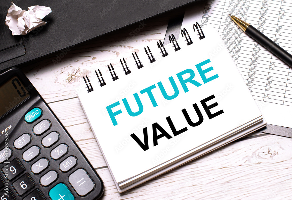 On a light-colored office table is a computer, a black calculator, a pen, and a notebook with the text FUTURE VALUE. Business concept. On a light-colored office table is a computer, a black calculator, a pen, and a notebook with the text FUTURE VALUE. Business concept.