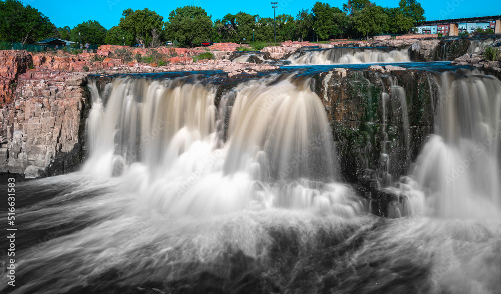 Waterfall over quartzite red rocks at Big Sioux River park in Sioux Falls, South Dakota. Long exposure photo of the silky flowing water. Waterfall over quartzite red rocks at Big Sioux River park in Sioux Falls, South Dakota. Long exposure photo of the silky flowing water.