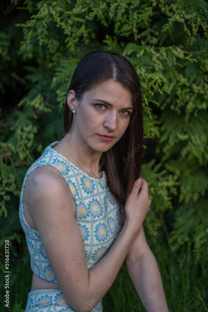 Naklejka premium Sensual serious woman is touching her hair and looking straight ahead. Natural picture of a pretty girl in the forest.