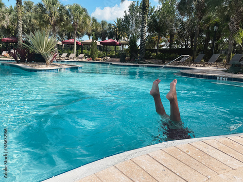 young boy with legs up in blue pool underwater hand stand resort vacation outdoors