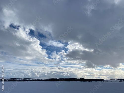 Multilayer cumulus clouds in the sky over a snowy plain.