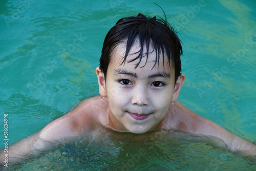 A small child on vacation in the pool with a ball enjoys a close-up vacation. Joy, childhood © Zinesh