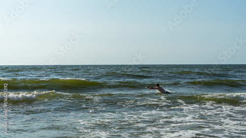 Teenager or a young man dives into the waves on the Baltic Sea, Curonian Spit, Kaliningrad region, Russia. Space for text