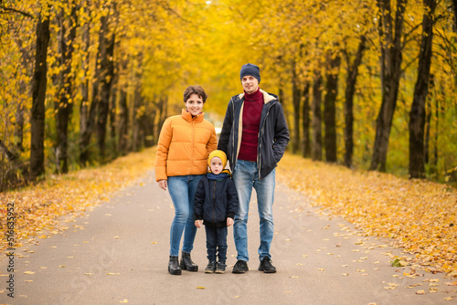 Happy family posing in autumn park and looking at camera, smiling outdoor in park at autumn.