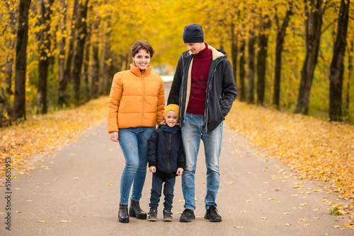 Happy family posing in autumn park and looking at camera, smiling outdoor in park at autumn.