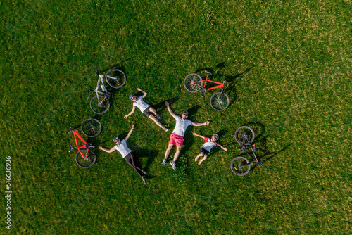 active parents with child have fun on the grass. drone photo. aerial view from above. family cycling on bikes