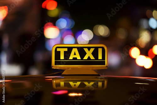Taxi sign on roof car in night city with bokeh effect