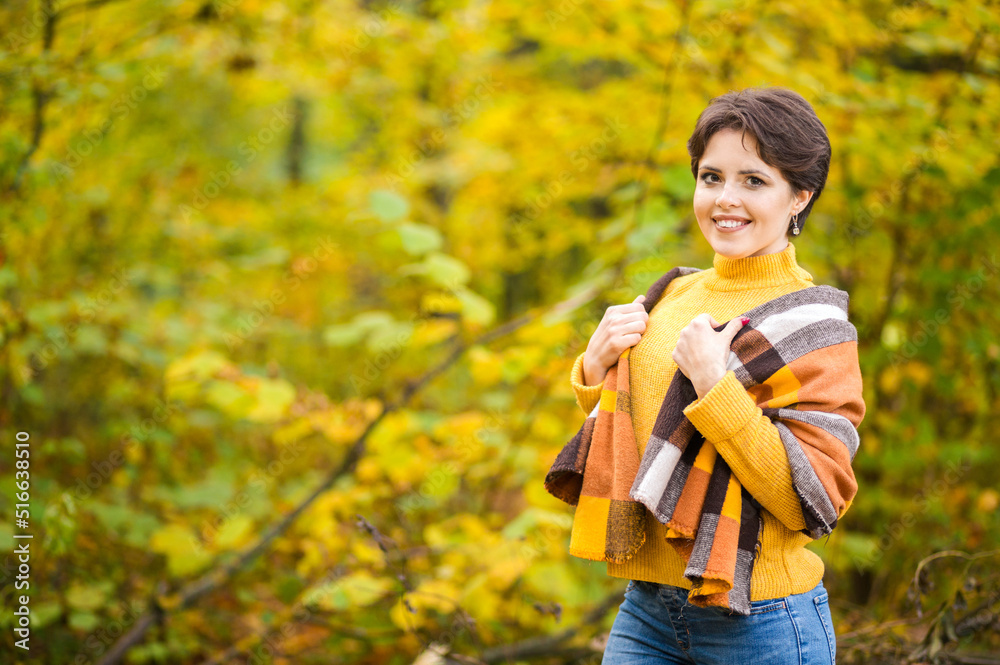Cheerful smiling young brunette wrapped in blanket in autumn forest Cheerful smiling young brunette wrapped in blanket in autumn forest