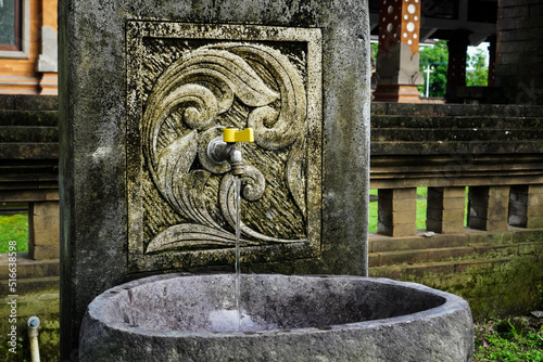 Tap Water running on the wall and stone bath