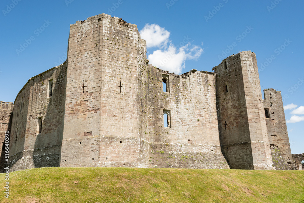 The great wall of Raglan castle on a sunny day. The medieval stone structure is a popular historical tourist attraction for visitors to Wales and the UK