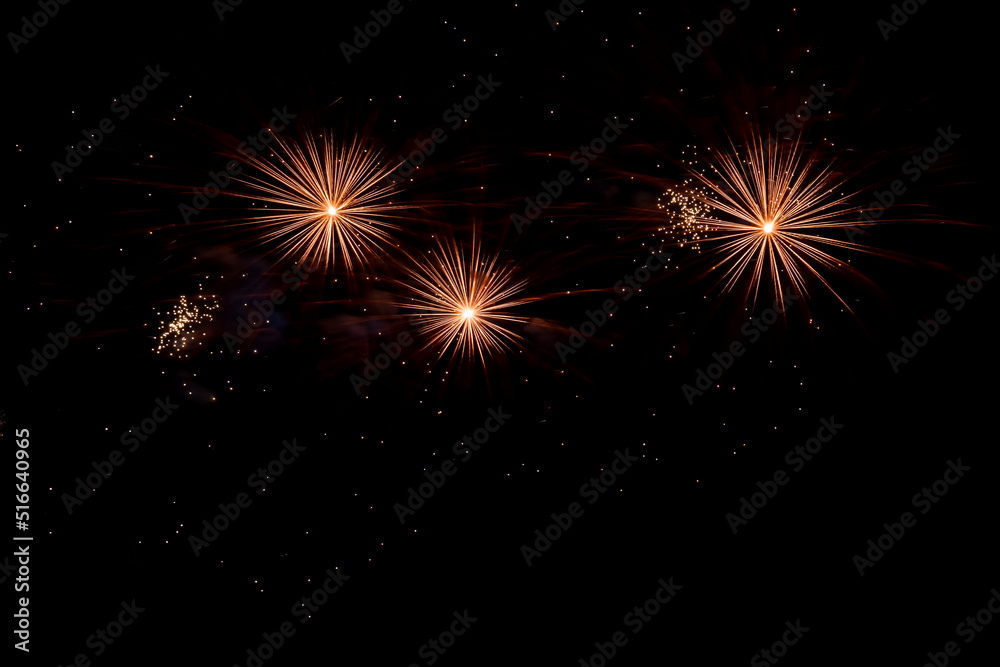 New Year's holiday fireworks. Bright beams of light from explosion of pyrotechnics against dark night sky. Beautiful fireworks in form of fiery stars and flowers.