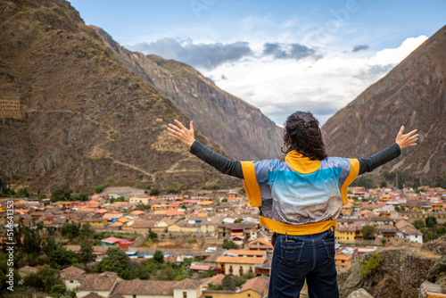 Woman looking at Ollantaytambo in the Sacred Valley in Cusco, Peru, from above on cloudy day photo