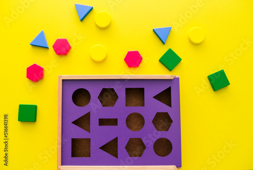 Billede på lærred Baby sorter with geometric figures from wood on a yellow isolated background