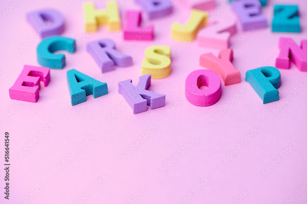 Fototapeta premium colorful wooden letters on pink background with copy space