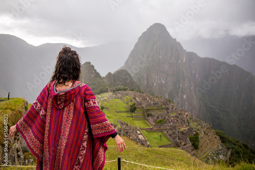 Woman Looking at Inca Citadel called Machupichu built of stones on the mountain, cloudy day, Peru photo