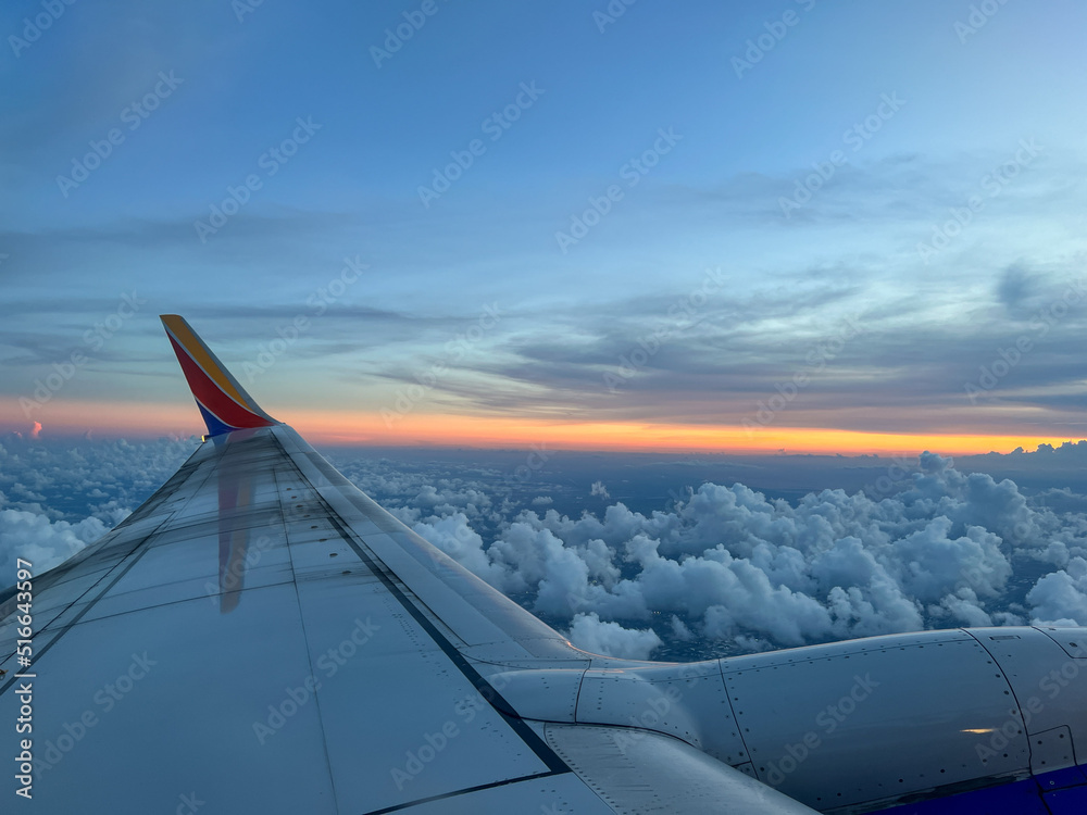 Fototapeta premium Southwest airplane wing flying above the clouds on a brigh blue sky sunny day.