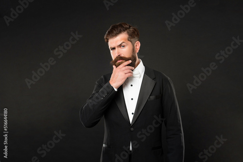 serious unshaven man in tuxedo bow tie. gentleman in formalwear on black background.