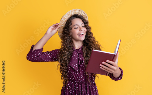 happy child with frizz hair recite book on yellow background photo