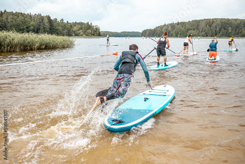 Paddling on a SUP board on a lake at sunny day. Stand up paddle boarding - awesome active outdoor recreation.