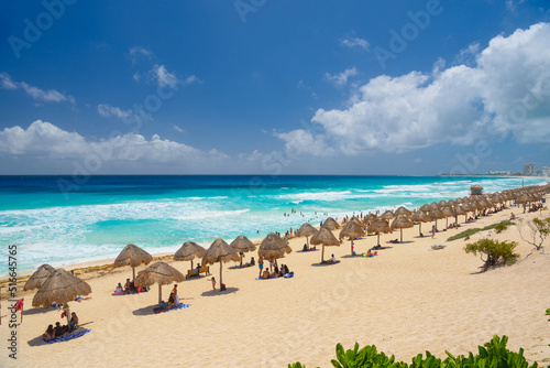 Fototapeta Naklejka Na Ścianę i Meble -  Umbrelas on a sandy beach with azure water on a sunny day near Cancun, Mexico
