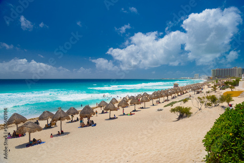 Umbrelas on a sandy beach with azure water on a sunny day near Cancun, Mexico © Eagle2308