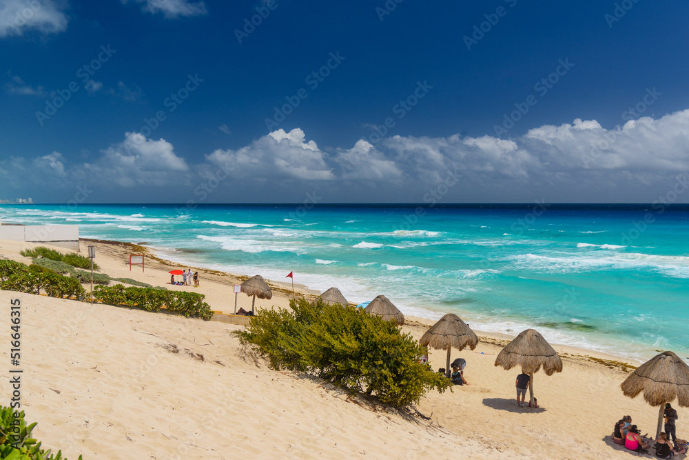 Umbrelas on a sandy beach with azure water on a sunny day near Cancun, Mexico Umbrelas on a sandy beach with azure water on a sunny day near Cancun, Mexico