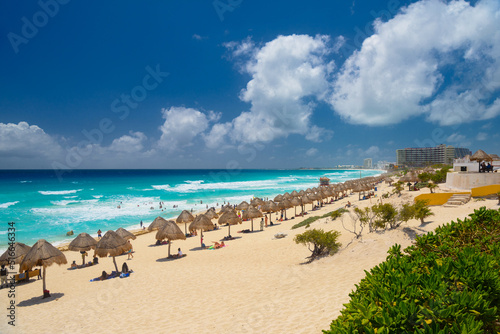 Umbrelas on a sandy beach with azure water on a sunny day near Cancun  Mexico