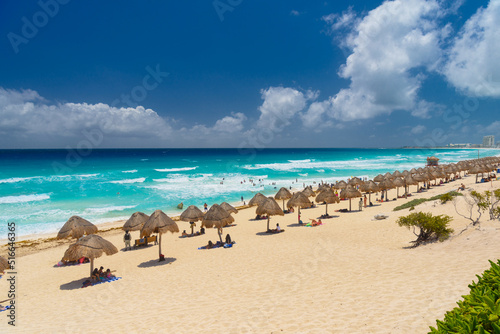 Umbrelas on a sandy beach with azure water on a sunny day near Cancun  Mexico