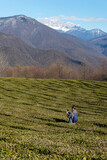 a woman tourist photographs the landscape of a tea plantation against the backdrop of mountains