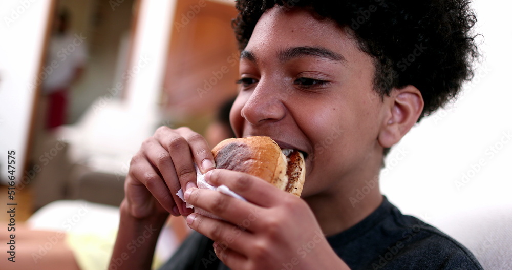 Child eating burger. Young boy taking a bite of hamburger Child eating burger. Young boy taking a bite of hamburger