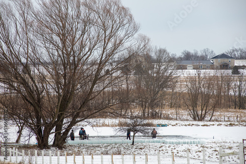 Amish men harvesting ice on a pond in winter in Holmes County, Ohio