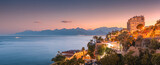 Aerial panoramic cityscape view of Antalya resort town with hotels and buildings and Taurus mountains in the background during majestic sunset twilight