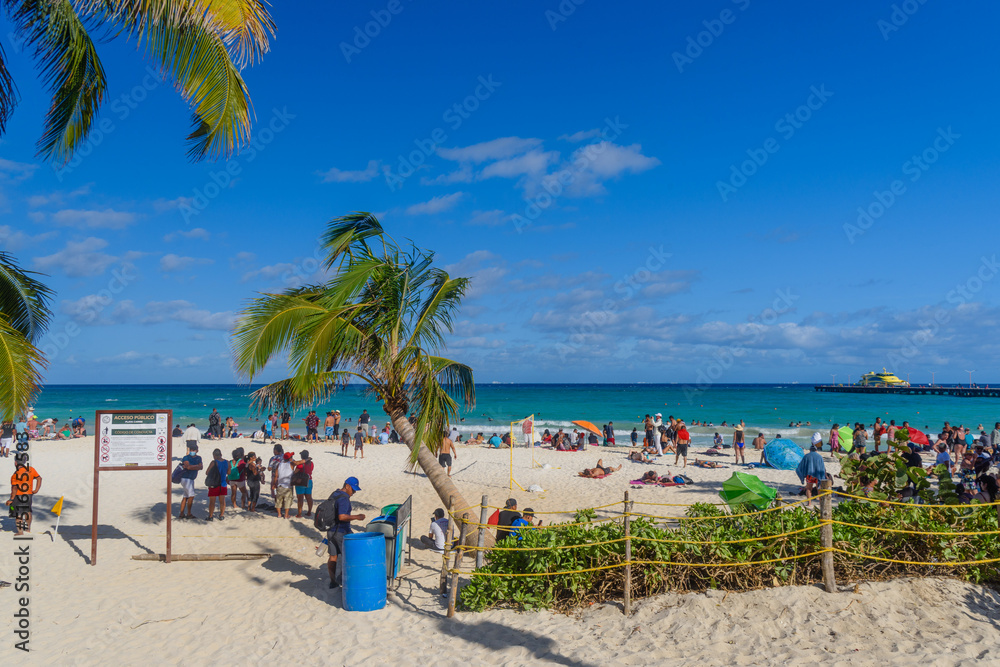 People on the sandy beach with cocos palms in Playa del Carmen, Yukatan, Mexico People on the sandy beach with cocos palms in Playa del Carmen, Yukatan, Mexico