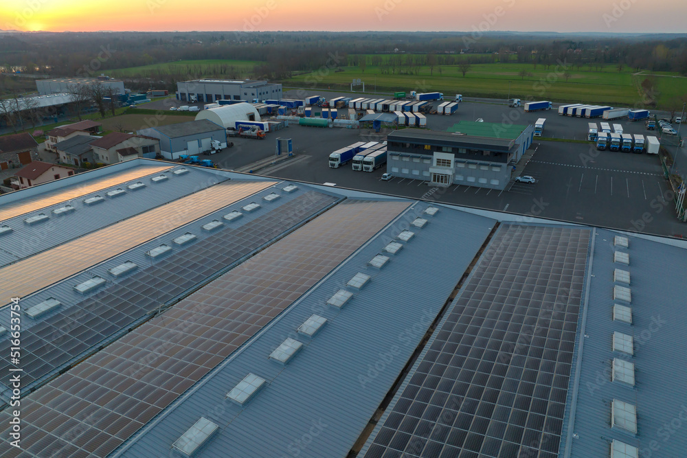 Aerial view of solar power plant with blue photovoltaic panels mounted on industrial building roof for producing green ecological electricity. Production of sustainable energy concept