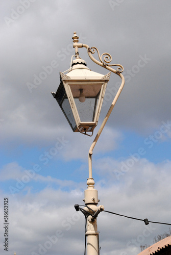 Old Vintage Cast Iron Lantern on Post against Cloudy Blue Sky 