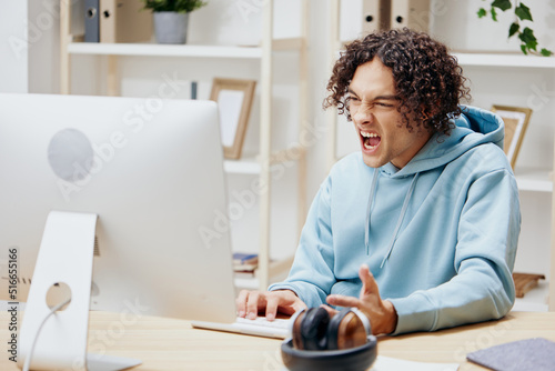 guy with curly hair in a blue jacket in front of a computer technologies