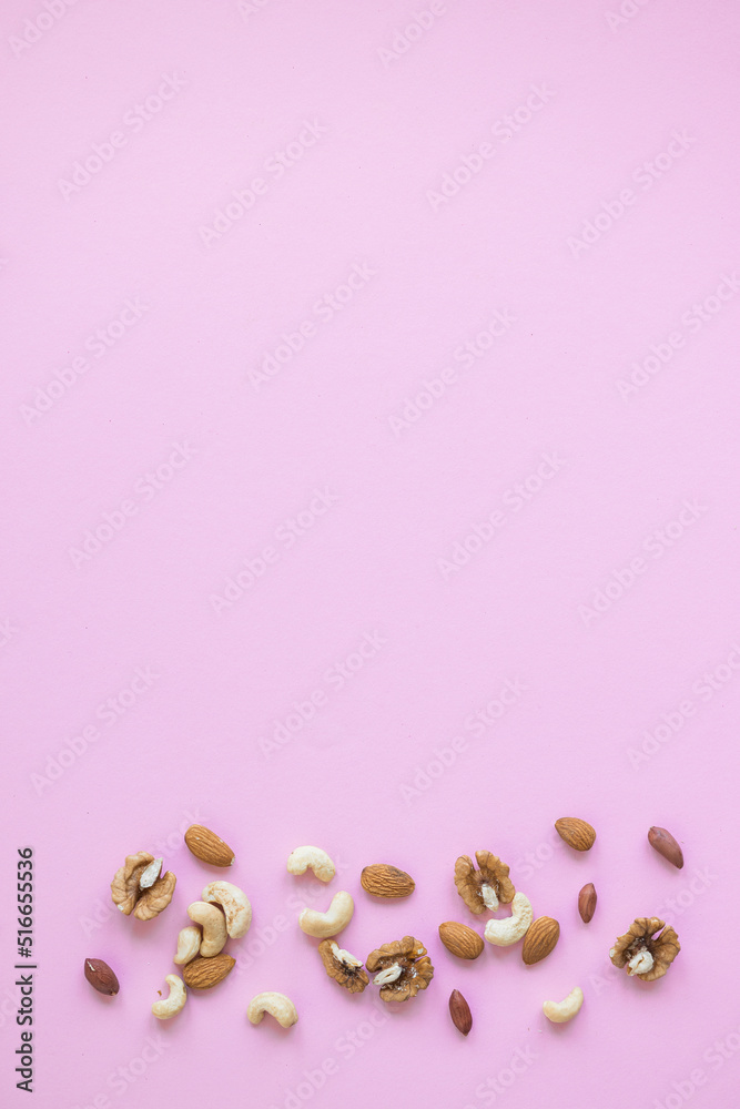 Creative layout made of hazelnut nuts, almonds, walnut, peanut, cashew on pink background. Flat lay. Food concept.