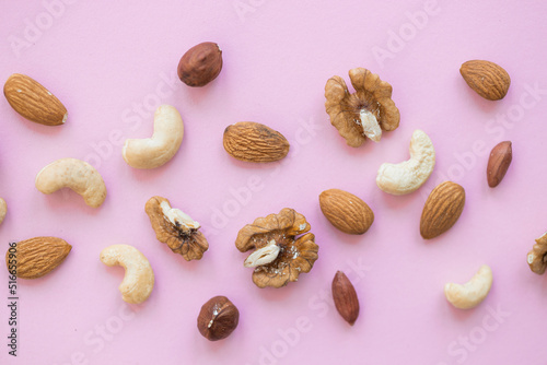 Creative layout made of hazelnut nuts, almonds, walnut, peanut, cashew on pink background. Flat lay. Food concept.