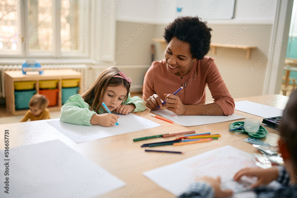 Little girl and black female teacher drawing on art class at preschool ...